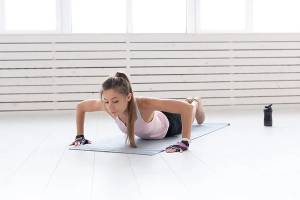 Estilo de vida saludable, deporte, concepto de personas: una mujer joven está haciendo ejercicio en el gimnasio o en casa. Ella está presionando en el traje deportivo — Foto de Stock