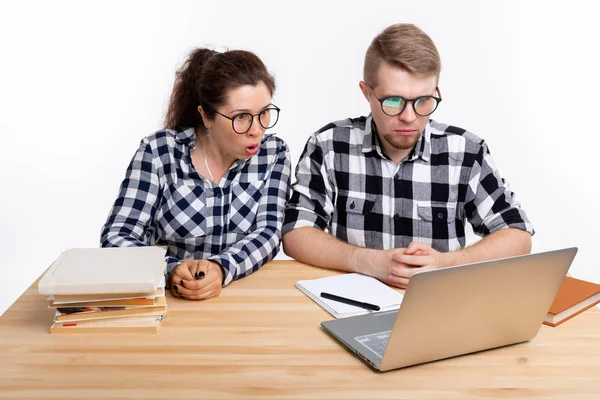 Istruzione, studenti, concetto di persone - un paio di adolescenti con gli occhiali hanno paura di qualcosa durante la ricerca nel computer portatile — Foto Stock