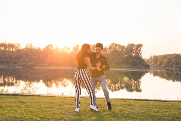 Romantic, social dance and people concept - young couple dancing bachata on the background of sunset