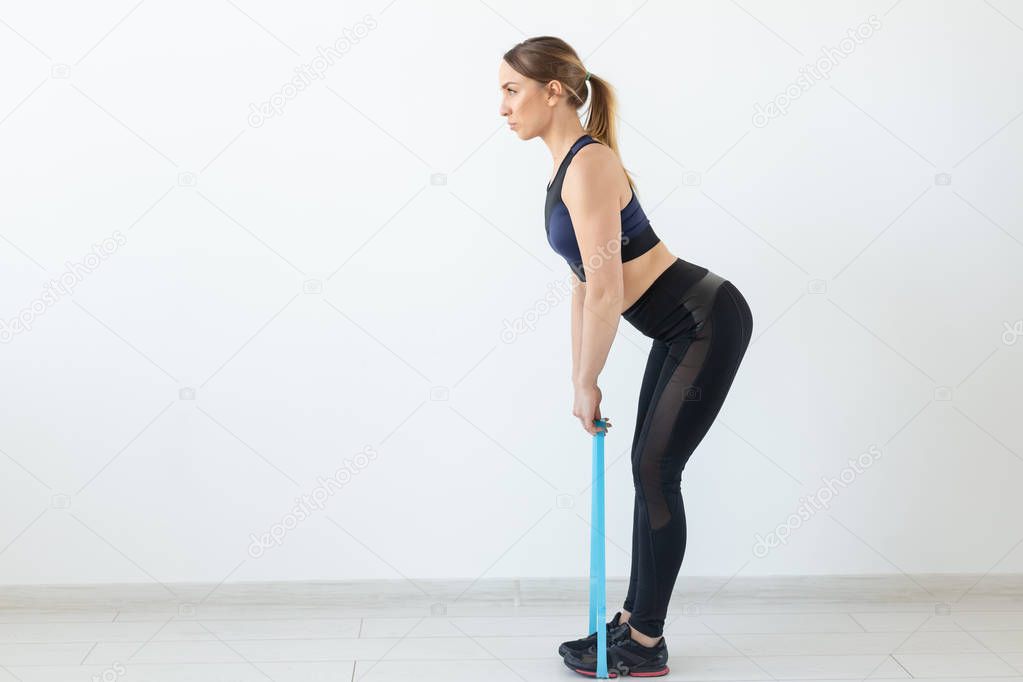 People, healthy and sport concept - Fit woman In sports clothes squatting with band