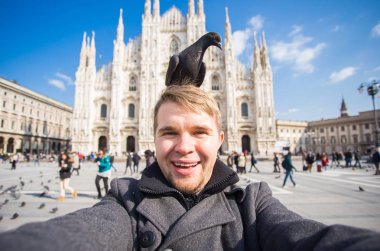 Kış seyahat, tatil ve kuşlar kavramı - selfie güvercinler yakınındaki Milan Katedrali Duomo di Milano, İtalya ile alarak genç komik adam.