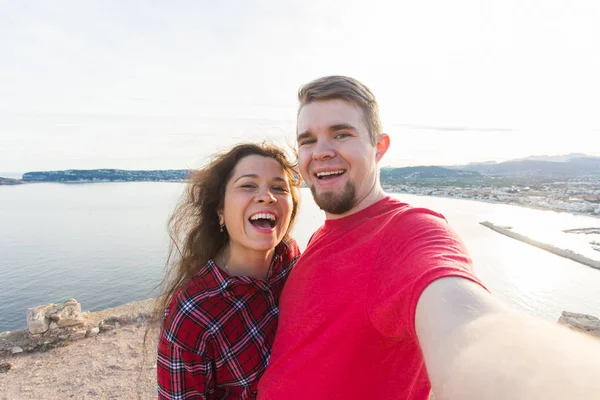 Conceito de viagem, férias e férias - Belo casal se divertindo, tirando selfie, rostos emocionais loucos e rindo . — Fotografia de Stock