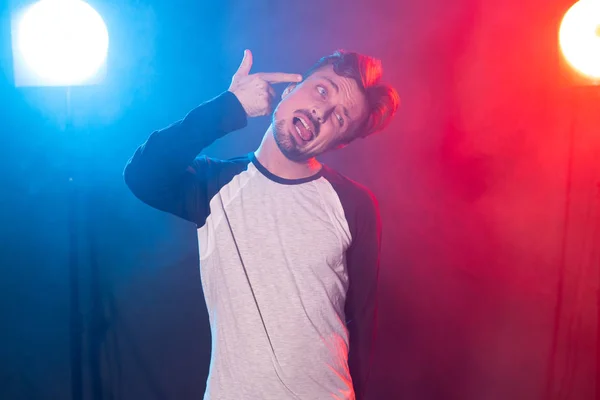 Divertido joven guapo Hipster representa con su mano un arma posando sobre un fondo rojo-azul. Concepto de fatiga y depresión — Foto de Stock