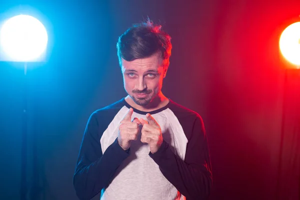 Hombre hipster barbudo joven guapo positivo posando sobre fondo azul-rojo y mostrando el dedo en la cámara. Concepto de y usted hizo su elección . — Foto de Stock