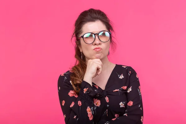 Gros plan portrait d'une jeune femme charmante et sérieuse dans des lunettes posant sur un fond rose. Concept de rêves et d'idées . — Photo