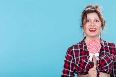 Diyet, tatlı ve abur cubur - mavi arka plan kopyalama alanı üzerinde lolipop ile kadın pin-up tarzı.