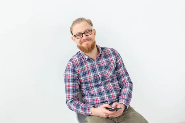 Jovem barbudo hipster homem segurando celular sobre o fundo branco — Fotografia de Stock