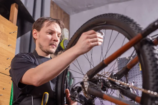 Een man monteur repareren van de fiets in zijn dienst — Stockfoto