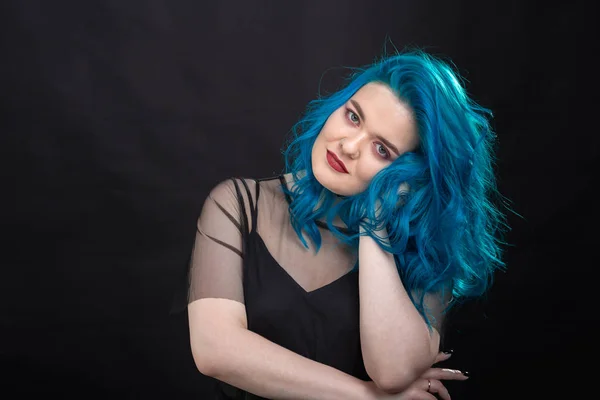 Pessoas e conceito de moda - Mulher jovem e atraente com batom preto e cabelo azul posando sobre fundo preto — Fotografia de Stock