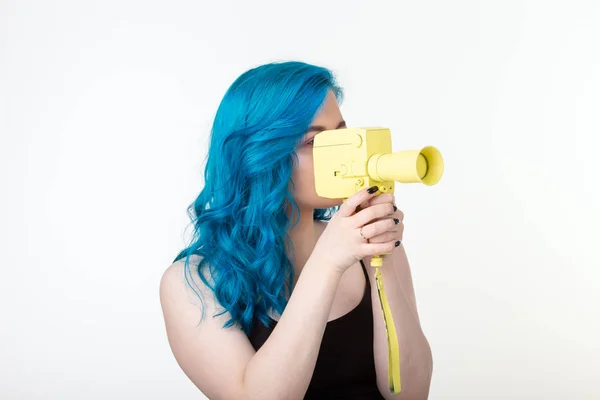 人、趣味、ファッションのコンセプト - 青い髪の美しい女の子は、白い背景に黄色のレトロなカメラを保持します — ストック写真
