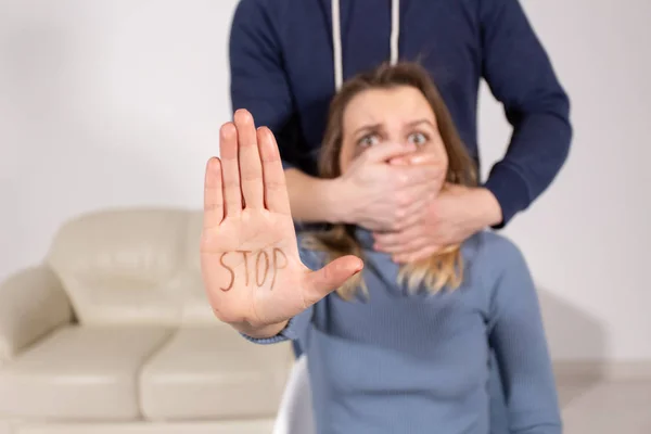 Las personas, la violencia doméstica y el concepto de abuso - Mujer muestra dejar de abusar de signo sobre los antecedentes de los hombres. Hombre cubre su boca con su mano — Foto de Stock