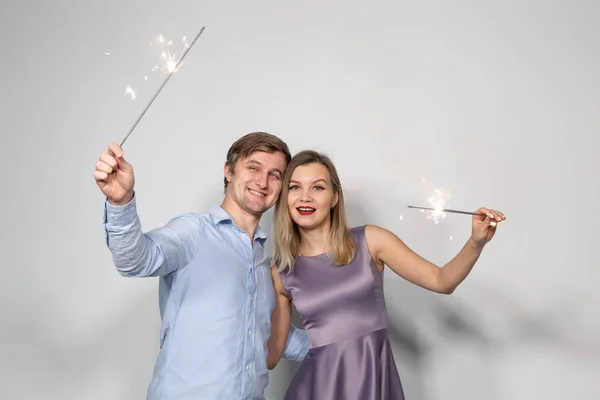 Festa, diversão e feriados conceito - jovem casal feliz com sparklers no fundo branco — Fotografia de Stock