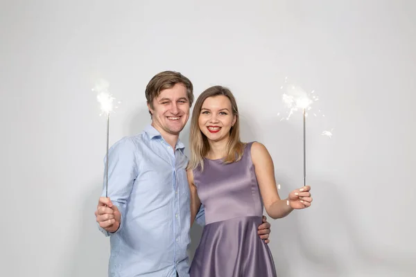 Conceito de feriados, festas e celebrações - jovem casal com brilhos no fundo branco — Fotografia de Stock