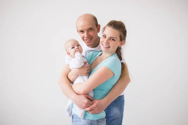 Orgullosa madre y padre sonriendo a su hija recién nacida sobre fondo blanco — Foto de Stock