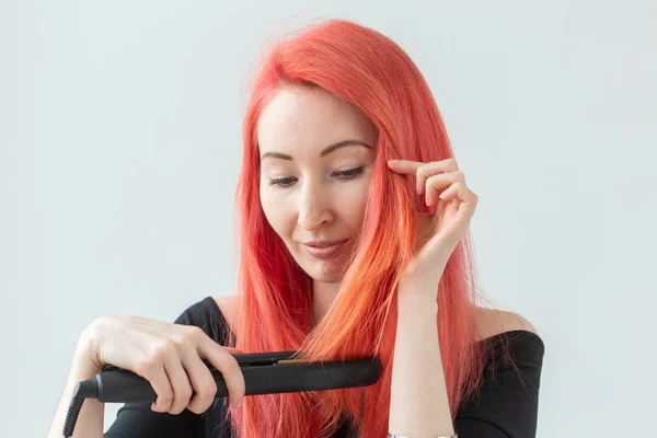 Frisur, Friseur- und People-Konzept - stylische rothaarige Frau mit Lockenstab auf weißem Hintergrund. — Stockfoto