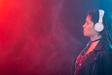 Rastalı genç bir kadın kulaklıklarındaki müziğin tadını çıkarıyor. Renkli arka planda fotokopi alanı ile birlikte.