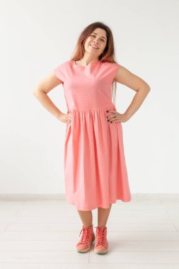 Beyaz bir duvarın arka planda poz parlak pembe elbise güzel genç neşeli kadın. Şık kadınsı görüntüler kavramı.