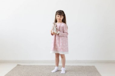 Beyaz odada oyuncak ile pembe elbiseli çocuk kız