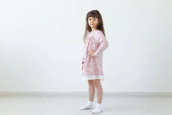 Trochę dumny brunetka dziewczyna w różowej sukni stoi na białym tle. Koncepcja stylowej odzieży dziecięcej i wieku przedszkolnym. Miejsce. — Zdjęcie stockowe