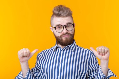 Gözlük ve sakallı Charming kendine güvenen genç moda hipster adam kendini sarı bir arka plan üzerinde poz gösterir. Reklam için yer. Özgüven ve başarı kavramı.