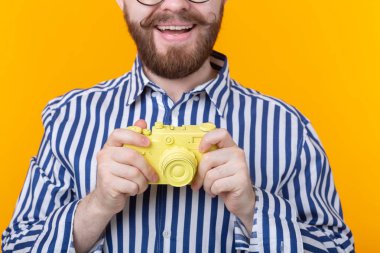 Bıyığı ve sarı arka planda sakal olan sarı kamera olan tanımlanamayan genç adam. Konsept fotoğrafçılığı ve hobi.