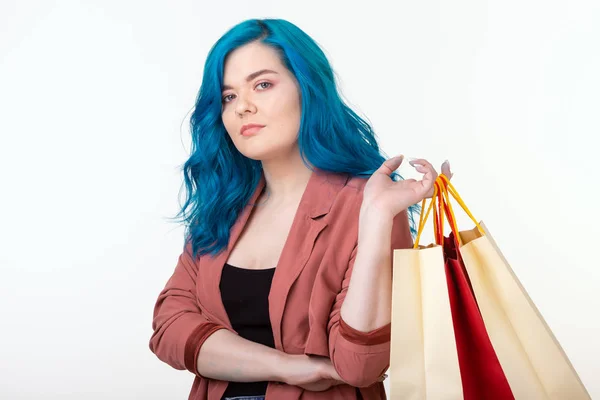 Sprzedaż, shopaholic i koncepcji konsumenta-piękna dziewczyna z niebieskim włosy stojące z torby na zakupy na białym tle — Zdjęcie stockowe