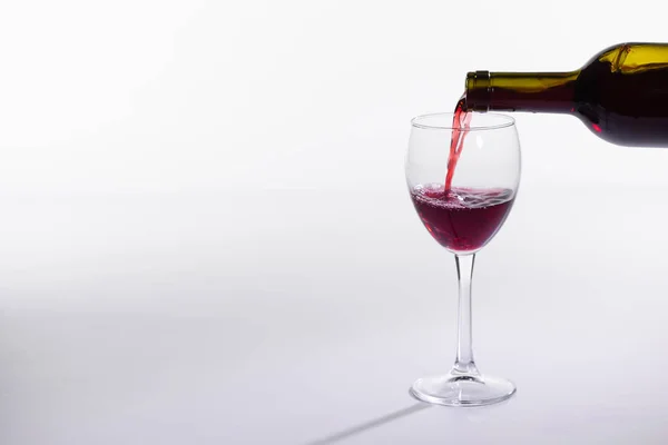 Pouring red wine into the glass on white background with copy space — Stock Photo, Image