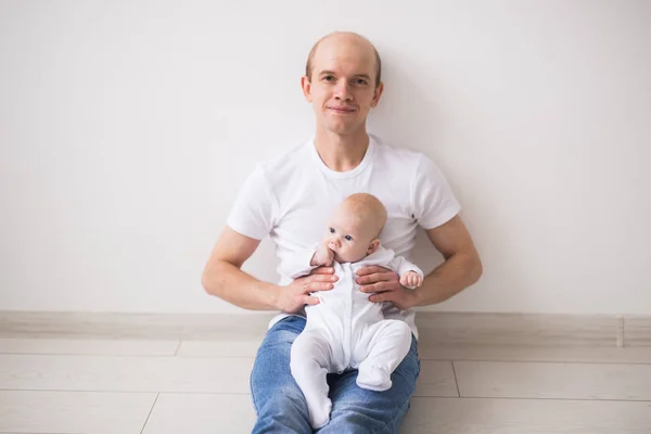 Concepto de bebé, familia y paternidad - padre calvo feliz sosteniendo a la hija del bebé de rodillas sobre un fondo blanco — Foto de Stock