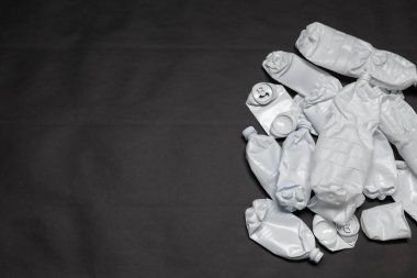 Çöplükten gelen plastik şişeler sağda siyah bir arka planda. Doğal kaynakların tıkanma kavramı ve plastik ürünlerin işlenmesi. Reklam alanı.