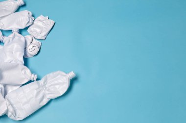 Buruşturulmuş plastik şişeler mavi bir arka plan üzerinde bırakılır. Reklam için yer. Plastik çöp ve çevre çöp kavramı.
