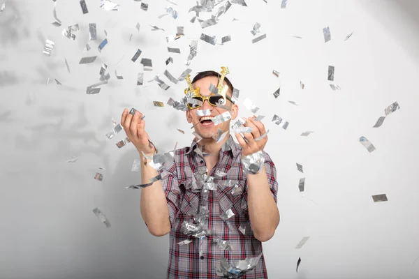 Gente, vacaciones y concepto de fiesta - chico divertido en gafas bailando en confeti sobre fondo blanco — Foto de Stock