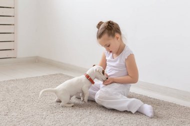 Çocuk, Evcil hayvanlar ve hayvanlar kavramı - küçük kız çocuk pijama ile Jack Russell Terrier köpek yavrusu yerde oynamak