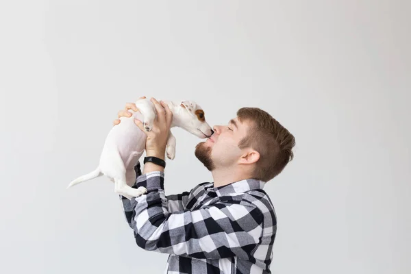 Люди, домашние животные и животные концепция - молодой человек целует Джек Рассел терьер щенок на белом фоне — стоковое фото