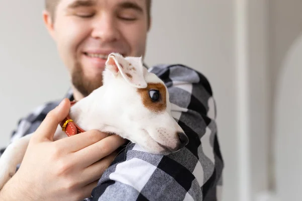 Concepto de personas, mascotas y animales - primer plano de hombre joven abrazando gato russell terrier cachorro sobre fondo blanco — Foto de Stock