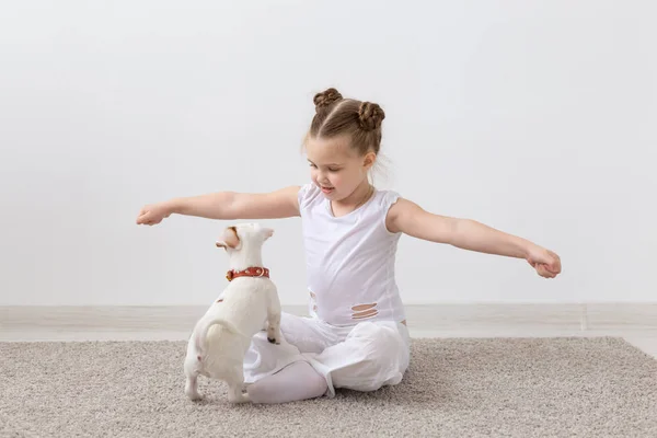 Concepto de la infancia, mascotas y perros - Pequeño cachorro y niña en camisa blanca divertirse — Foto de Stock