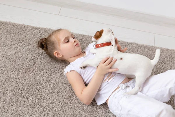 Pet, infância e conceito animal - Retrato de menina criança deitada no chão com cachorro Jack Russell Terrier — Fotografia de Stock