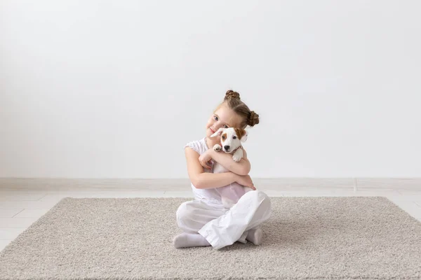 Concepto de perros, niños y mascotas - niña pequeña sentada en el suelo con un lindo cachorro — Foto de Stock