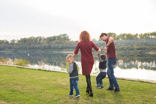 Parent, childhood and nature concept - Family playing with two sons by the water — Stock Photo, Image