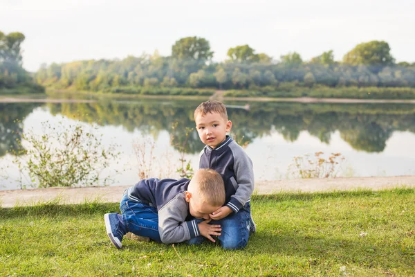 Crianças e conceito de natureza - Dois irmãos sentados na grama sobre o fundo da natureza — Fotografia de Stock