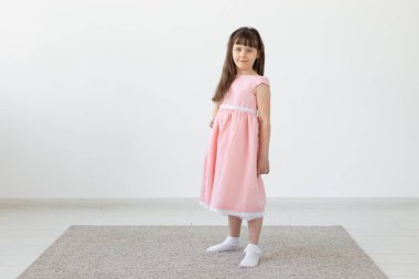 Pembe bir elbise beyaz bir arka plan üzerinde poz güzel küçük esmer kız. Sevimli çocuklar kavramı. Kopyalama alanı