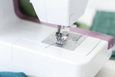 Mor iplik ile bir dikiş makinesi ayak yakın çekim iş için hazır ve yeni bir tasarım ürünü dikiş. Tasarımcı terziliği konsepti.