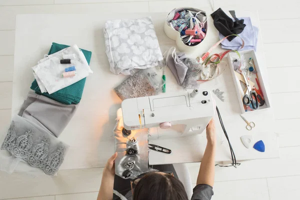 Tailor, fashion and seamstress concept - young female fashion designer in her showroom, top view