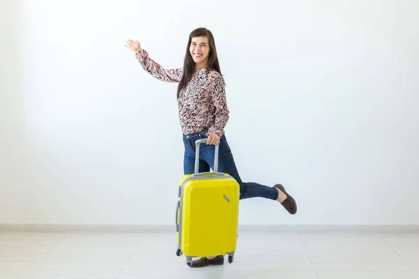 Jovem de pé com uma mala amarela no fundo de uma parede branca com espaço de cópia. O conceito de novas descobertas e a disponibilidade de viagens . — Fotografia de Stock