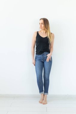 Stil ve insan kavramı - beyaz duvar üzerinde duran kot genç kadın ve seksi gibi görünüyor
