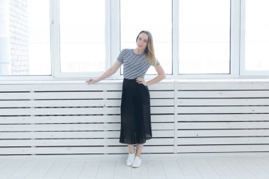 Gençlik, stil ve insan kavramı - siyah etek ve spor ayakkabı pencerenin yanında duran genç kadın