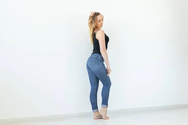 Стиль, концепція людей - молода жінка в джинсах і чорній сорочці, що стоїть на білому тлі з копіювальним простором — стокове фото