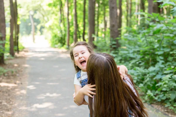 Rodina, rodičovství a příroda koncept - matka s dcerou baví v zeleném parku — Stock fotografie