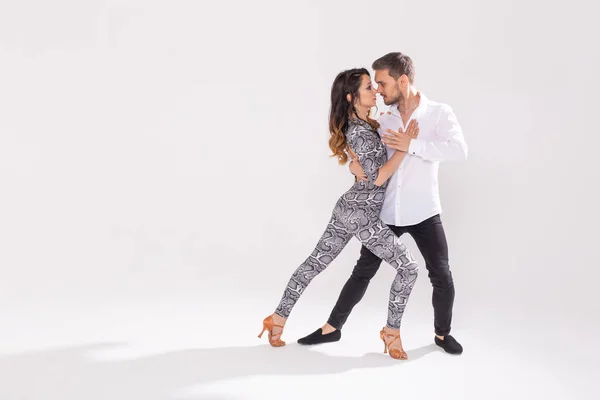 Социальный танец, бачата, кизомба, зук, концепция танго - мужчина обнимает женщину, танцуя на белом фоне с копировальным пространством — стоковое фото