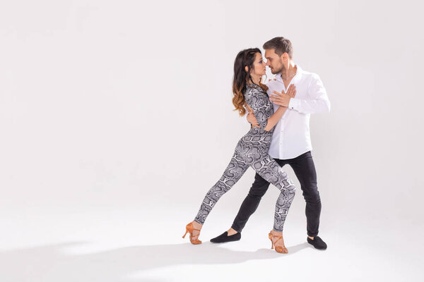 Social dance, bachata, kizomba, zouk, tango concept - Man hugs woman while dancing over white background with copy space