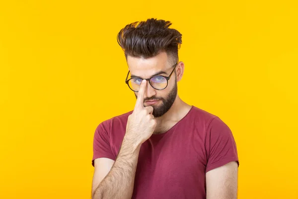 留着胡须的年轻时髦男子拿着眼镜,站在黄色背景上。关注的概念和艰难的选择 — 图库照片